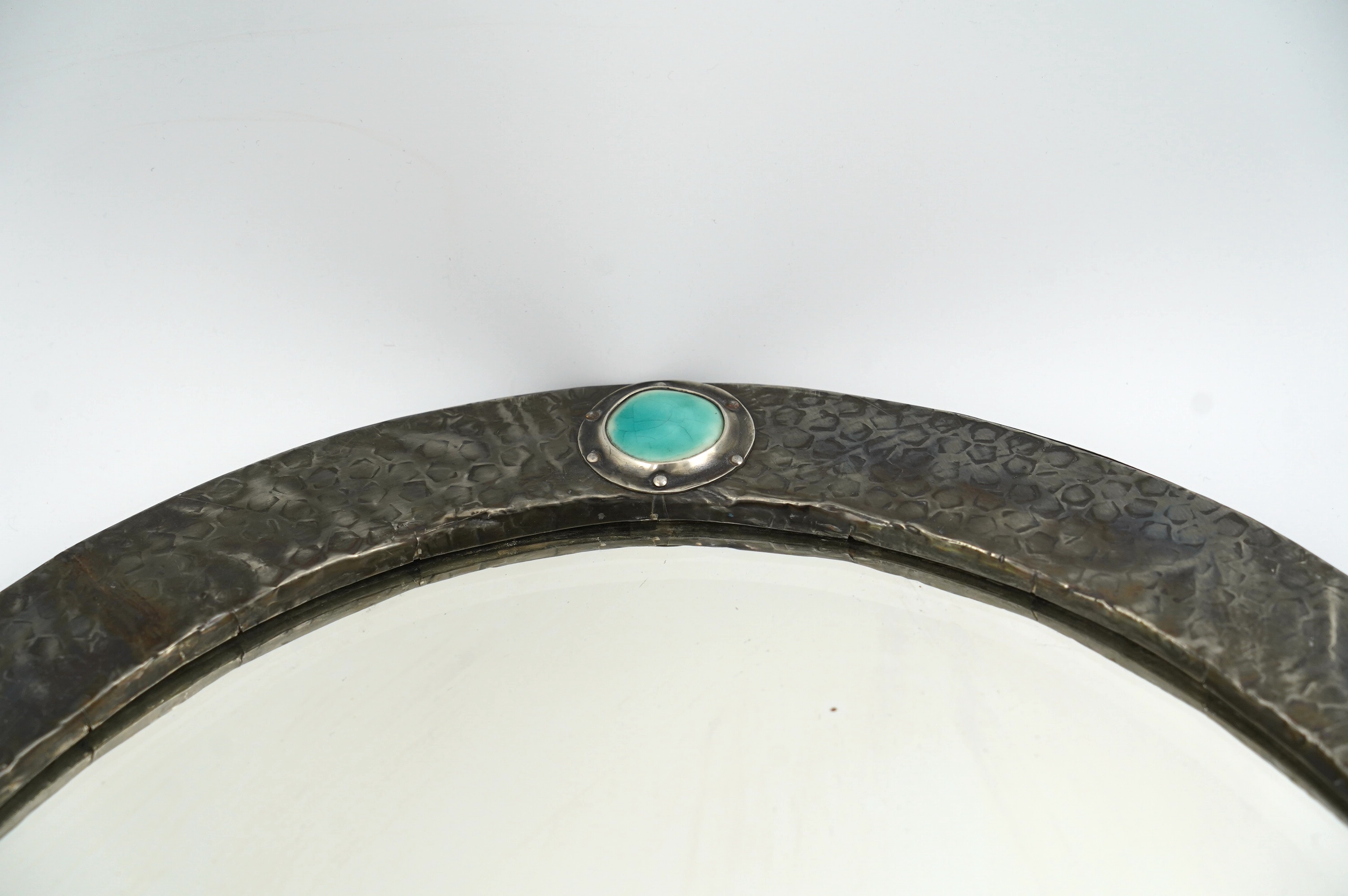 An Arts & Crafts pewter framed wall mirror inset with turquoise 'Ruskin stones'